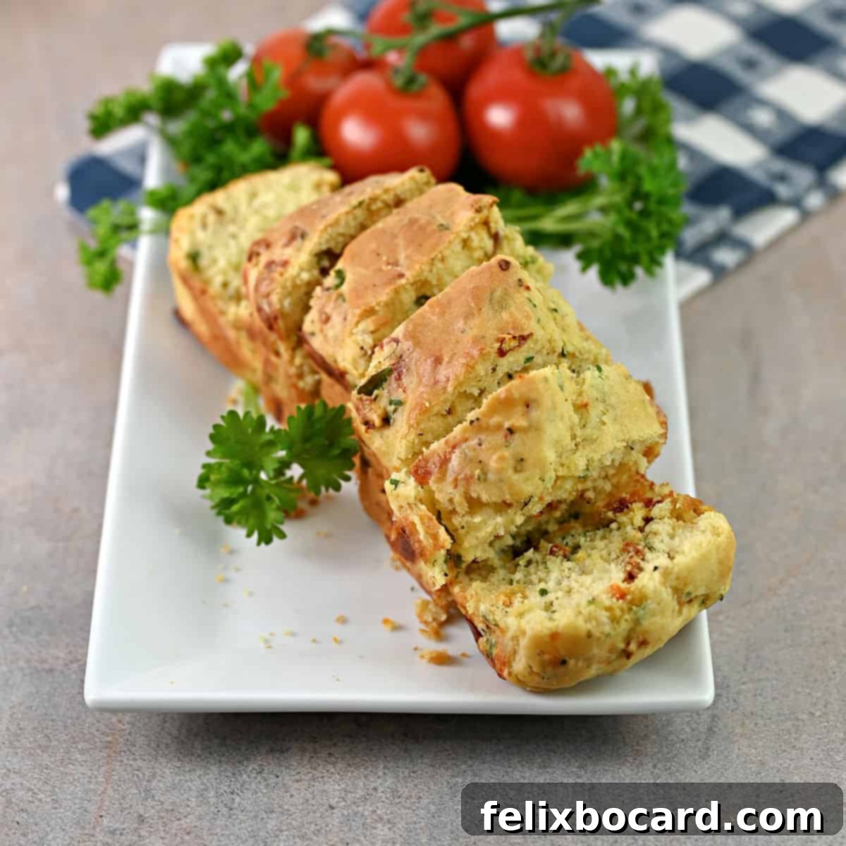 Savory Sun Dried Tomato Quick Bread 10 A close-up shot of a sliced mini loaf of sun-dried tomato bread on a serving platter, showing its soft interior with visible tomatoes and cheese.