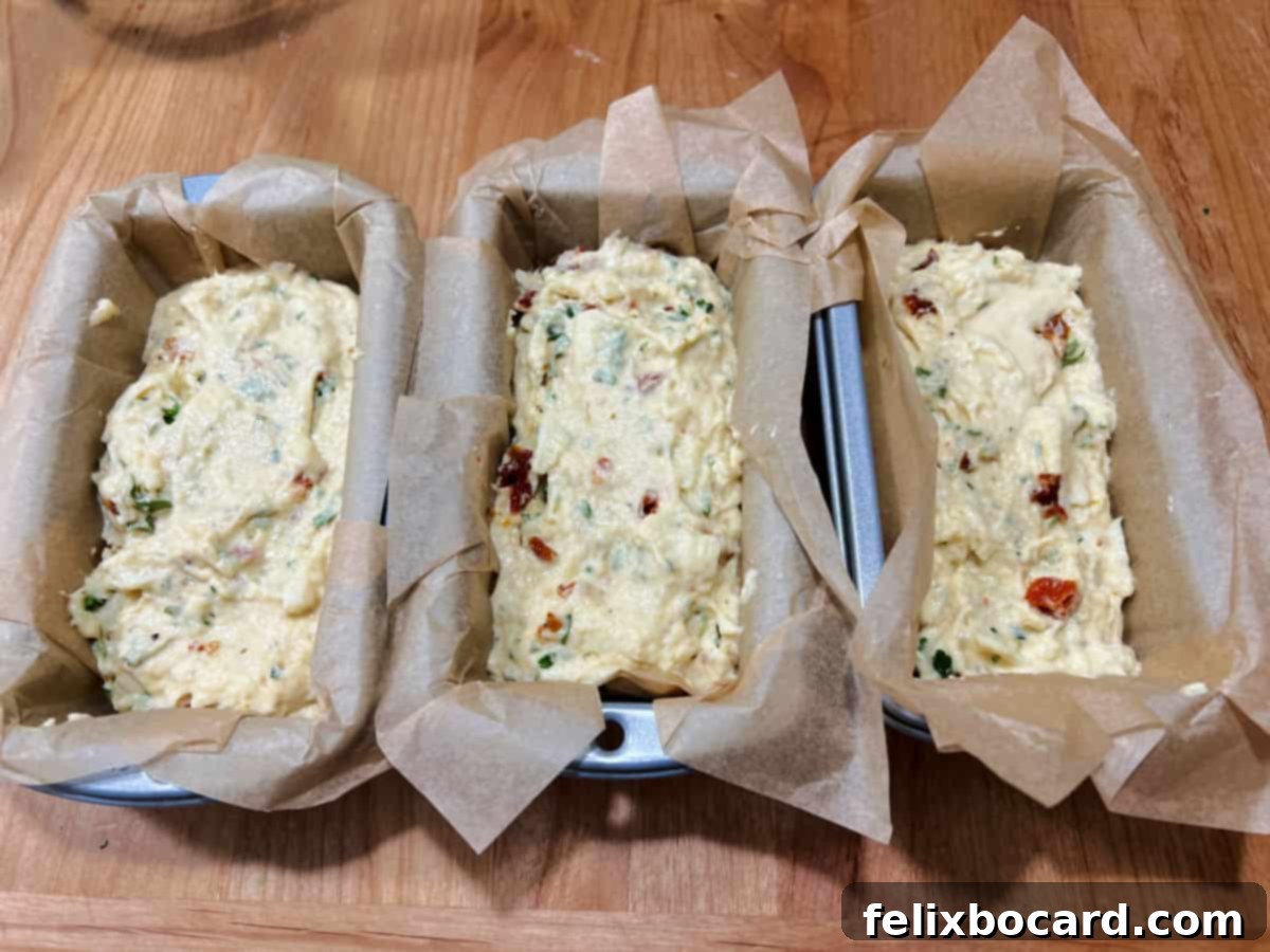 Savory Sun Dried Tomato Quick Bread 6 Bread batter evenly transferred into three mini loaf pans lined with parchment paper, ready for baking.