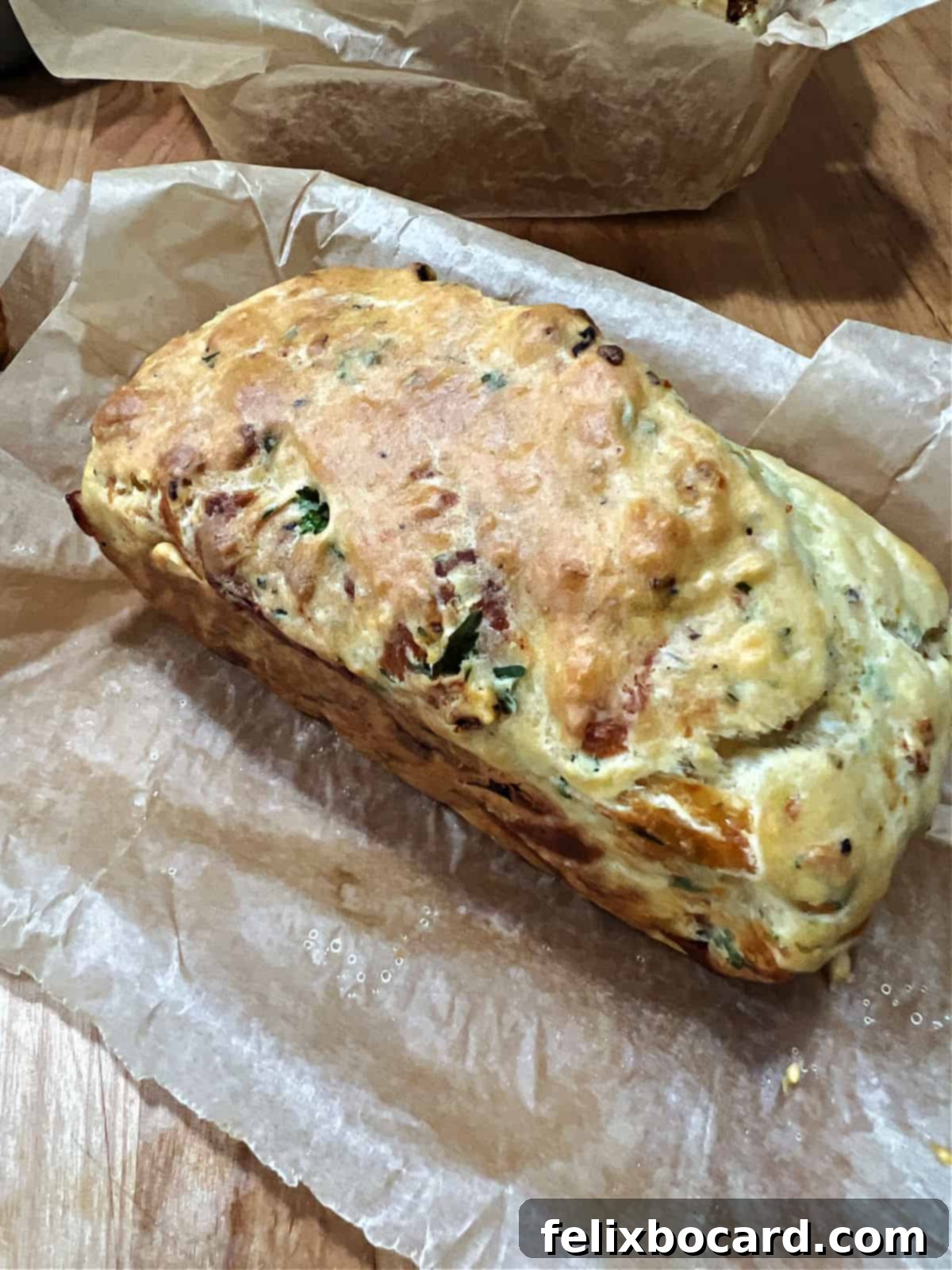Savory Sun Dried Tomato Quick Bread 7 A freshly baked mini loaf of sun-dried tomato bread cooling on a wire rack, still in its parchment paper lining.