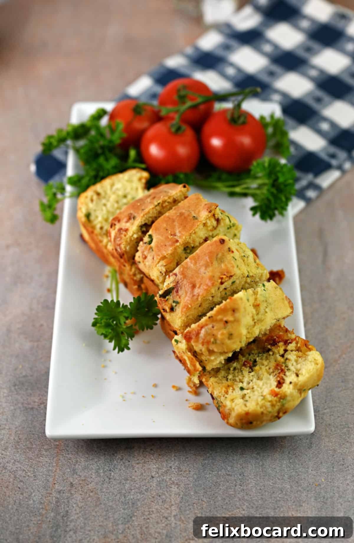 Savory Sun Dried Tomato Quick Bread 9 A beautifully sliced mini loaf of sun-dried tomato bread arranged on a serving platter, garnished with fresh parsley and cherry tomatoes.