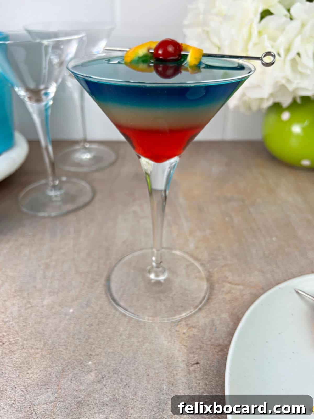 A finished rainbow cocktail with an orange slice garnish, emphasizing the drink's vibrant appeal.