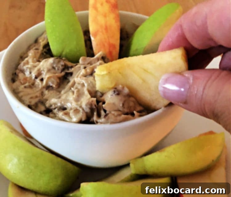 hand holding an apple slice dipping into heath bar dip