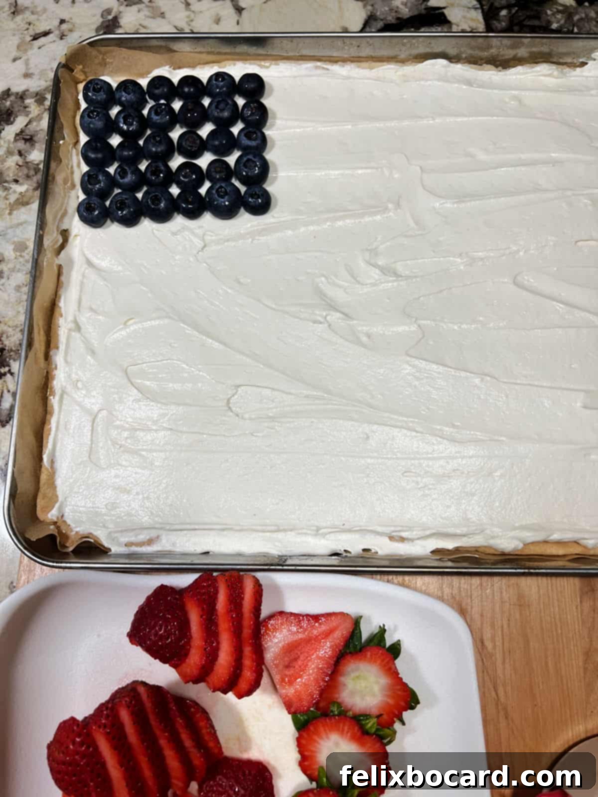 A rectangle of blueberries forming the 'union' on the upper left corner of the frosted fruit pizza.