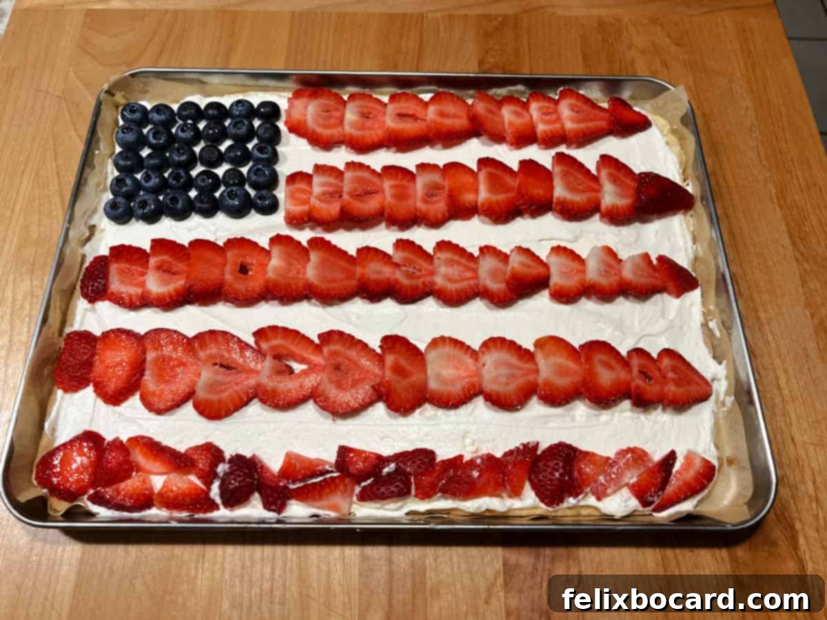 A fully assembled American Flag Fruit Pizza, with blueberry rectangle and red strawberry stripes on a white frosting base.