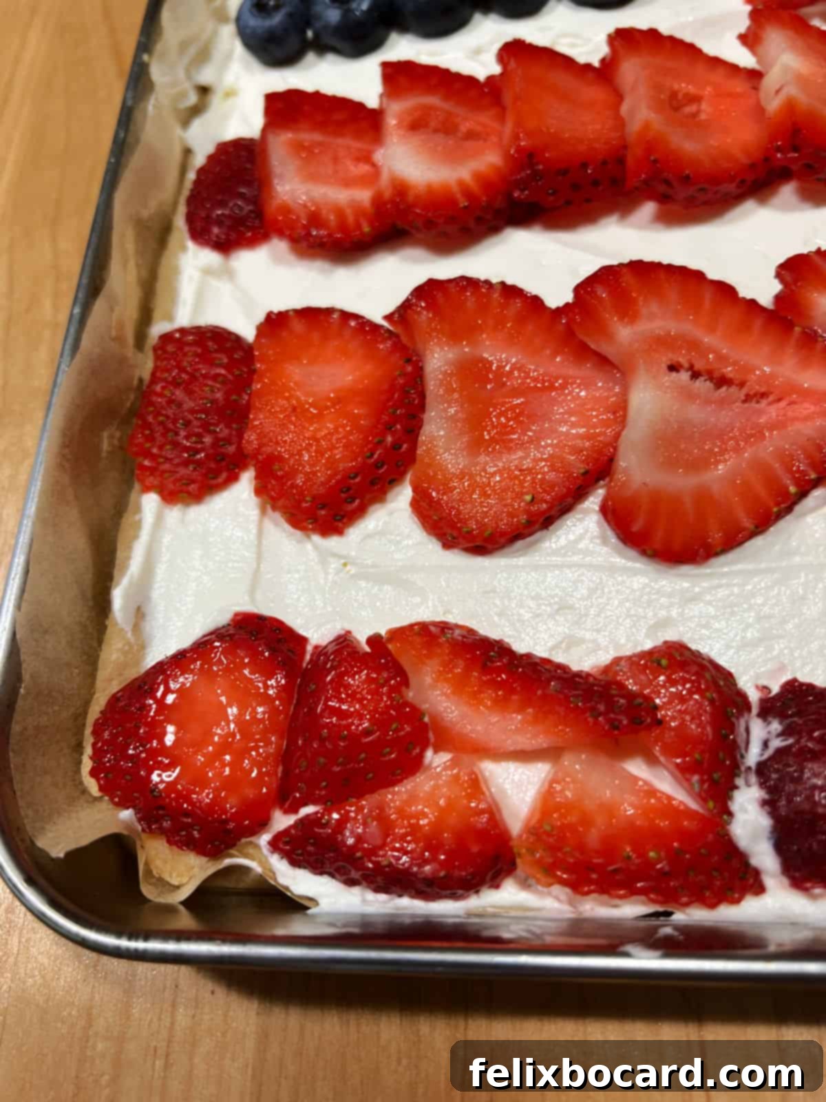 Close-up of smaller strawberry pieces used to form the bottom stripe of the fruit pizza flag, showcasing resourceful decorating.