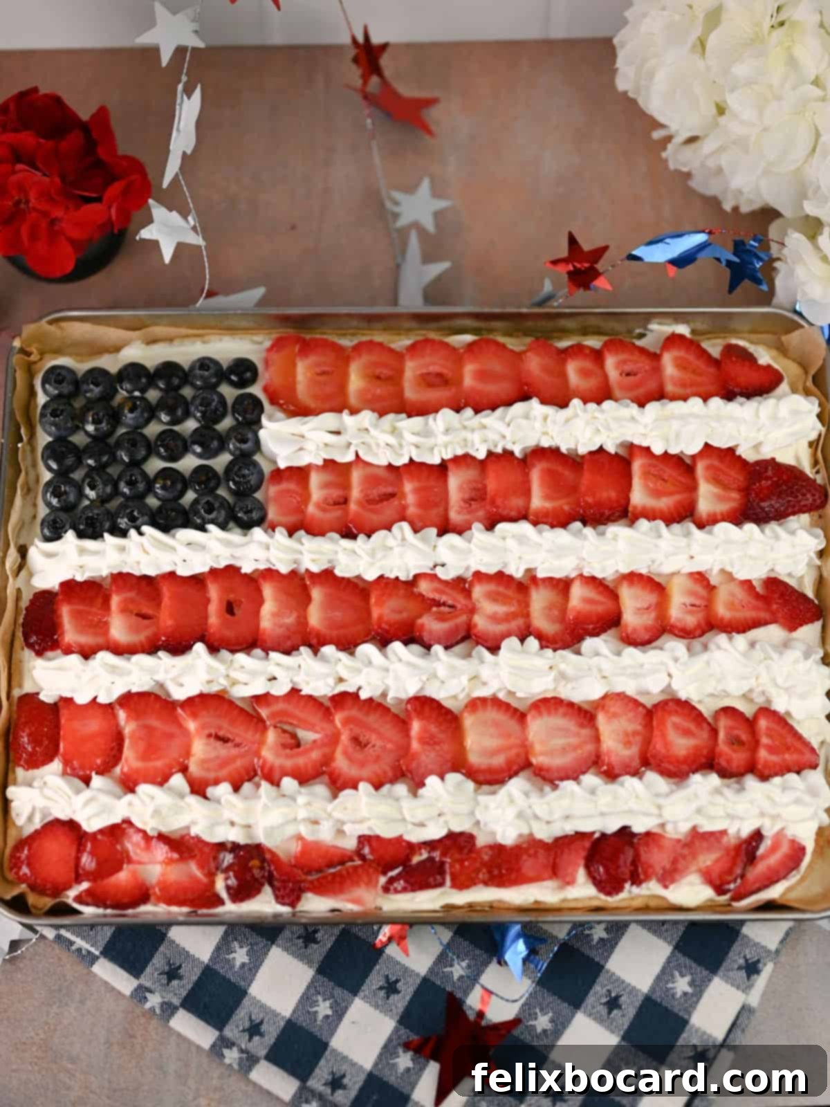 An American Flag Fruit Pizza in its pan, showcasing defined white stripes made with piped Cool Whip, ready to be served.