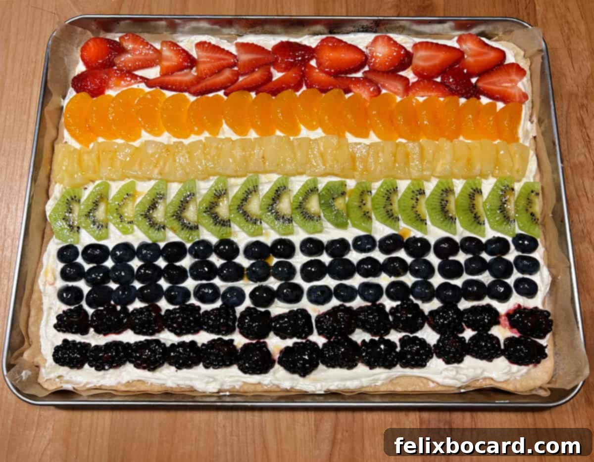 A colorful fruit pizza decorated to resemble the Pride flag, with distinct bands of fruit.
