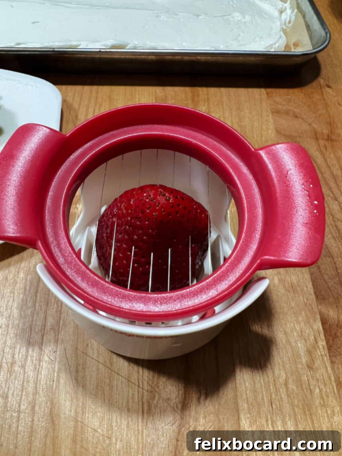 A strawberry being sliced using an egg slicer for uniform pieces.