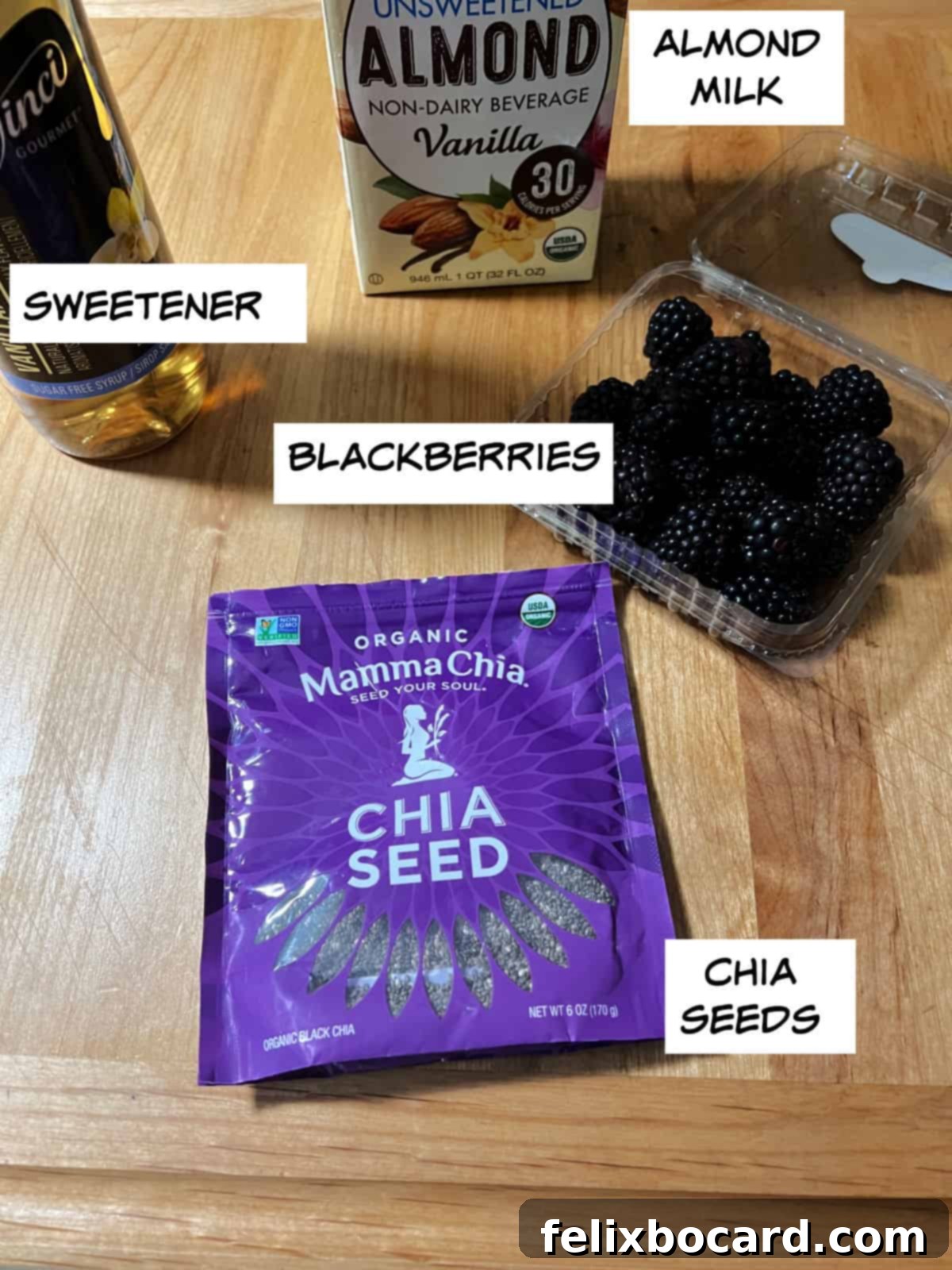 Key ingredients for Blackberry Chia Seed Pudding: almond milk, fresh blackberries, chia seeds, and a bottle of sweetener.