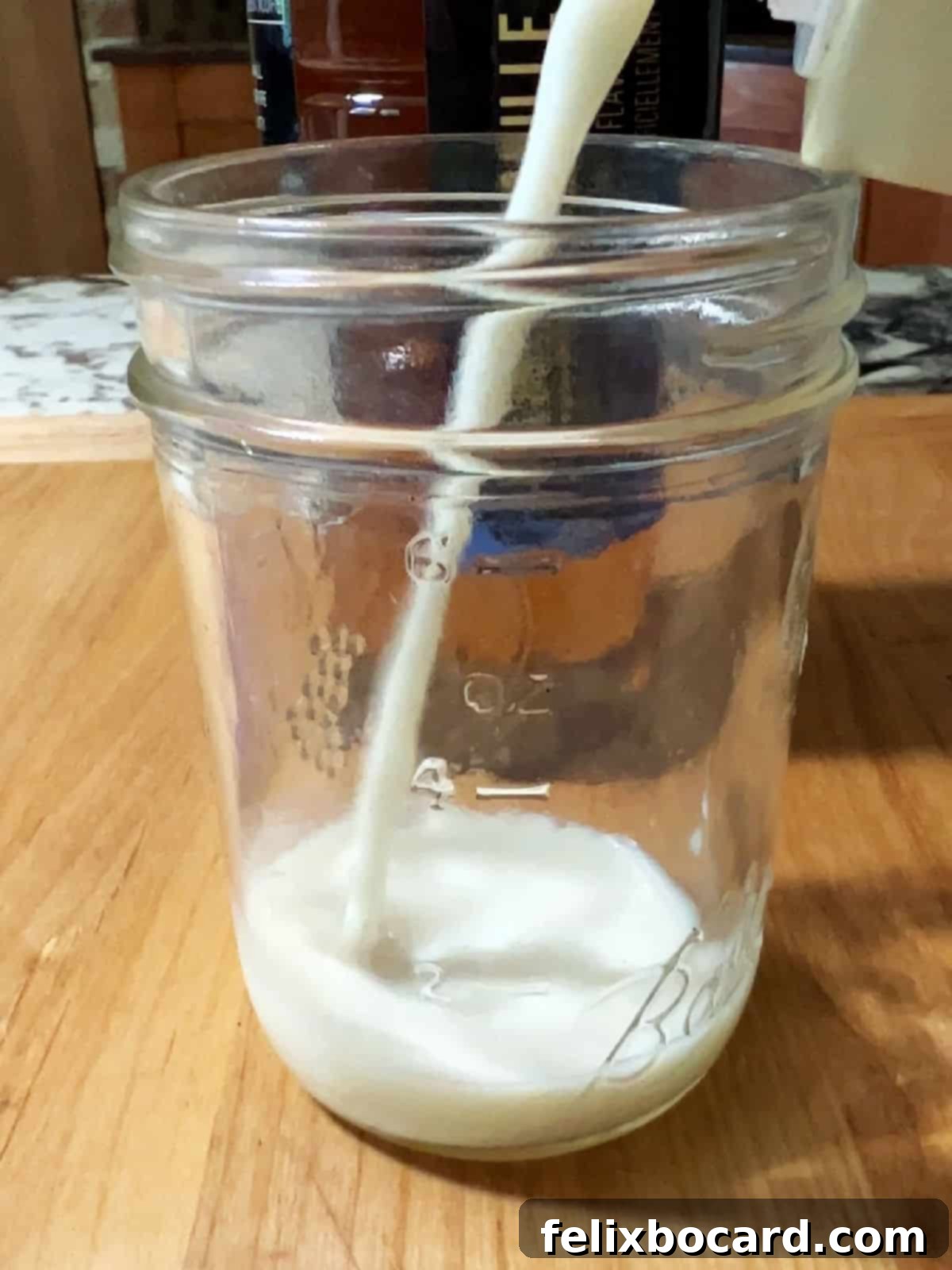 Almond milk being poured into a glass jar.