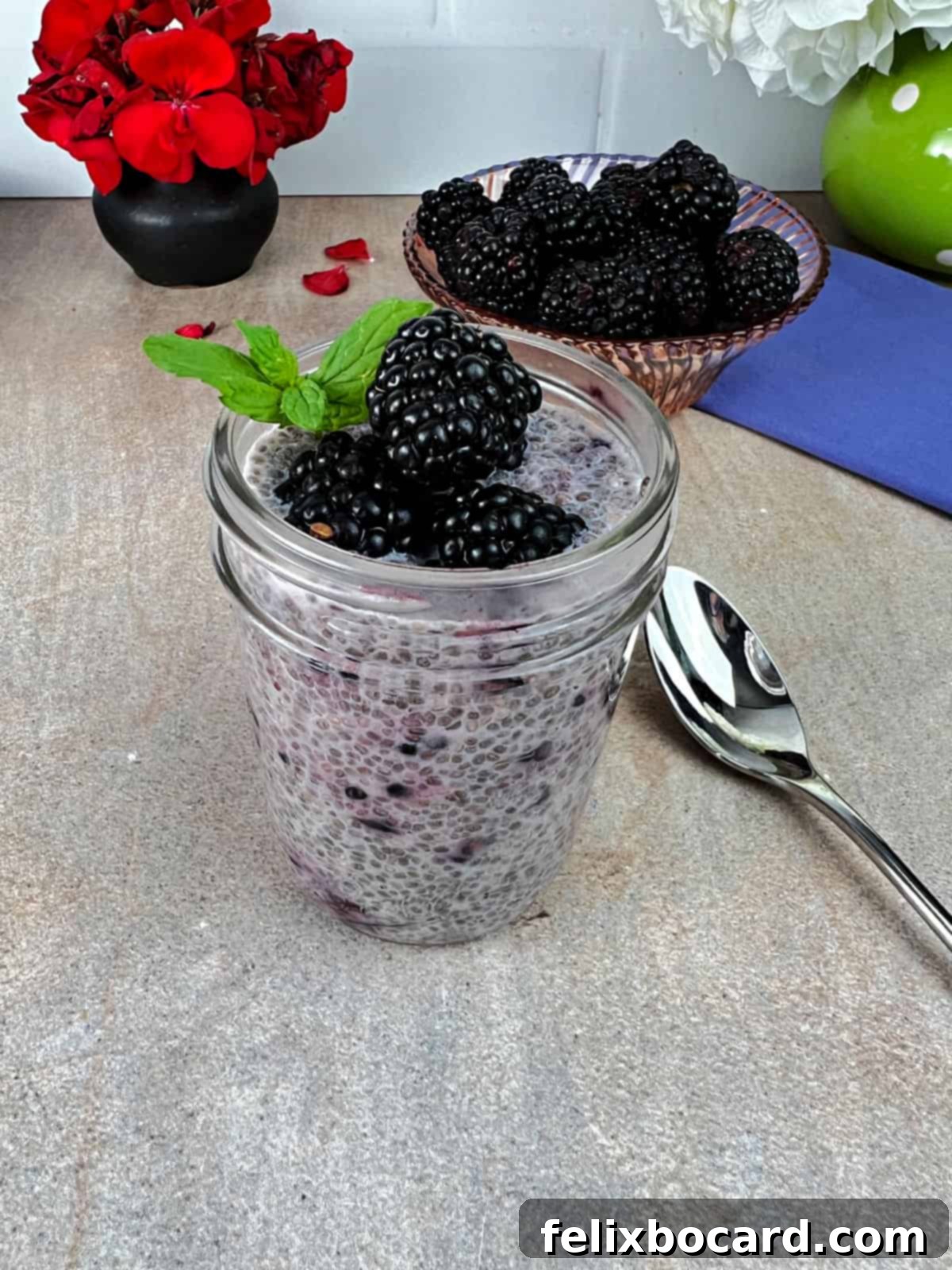 A finished jar of Blackberry Chia Pudding, beautifully garnished with fresh blackberries and a sprig of mint, ready to be enjoyed.