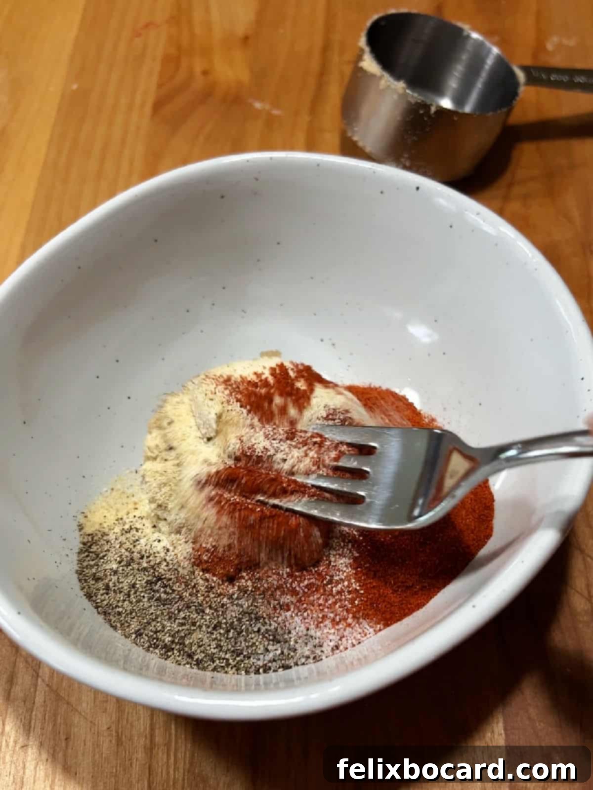 Using a fork to mix the spices together.