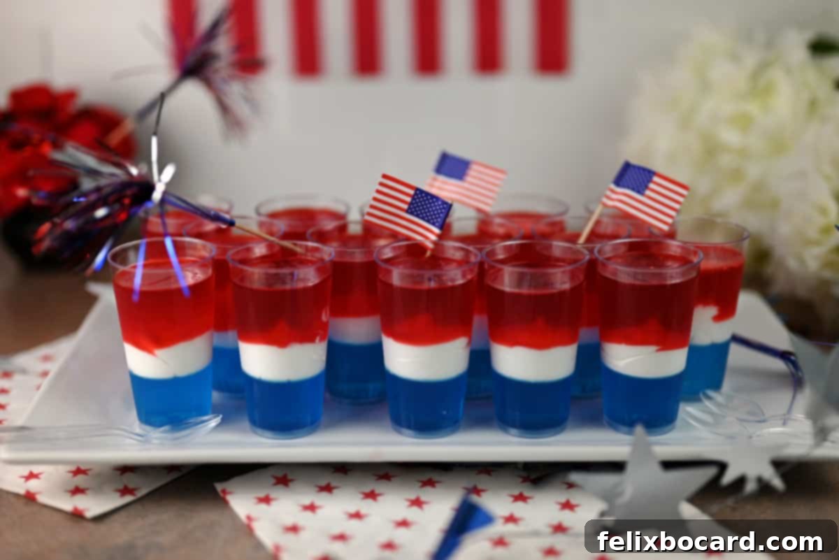 White serving plate filled with red, white, and blue jello shots, garnished with small flags.