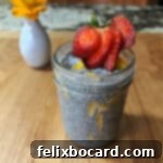 A small jar filled with mango chia seed pudding, garnished with strawberry.