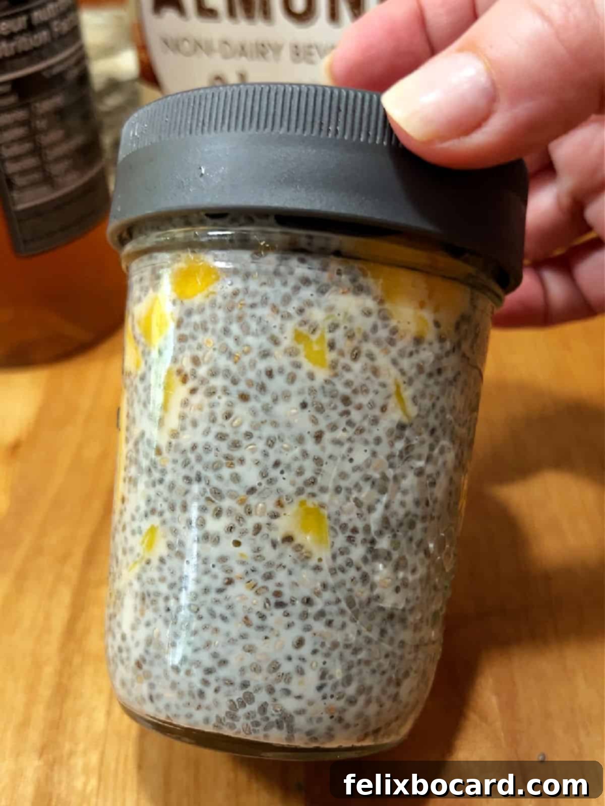A glass jar with mango chia pudding mixture, covered and ready for refrigeration.