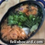 Fresh vegetable broth with collected scraps in a pot, ready for straining.