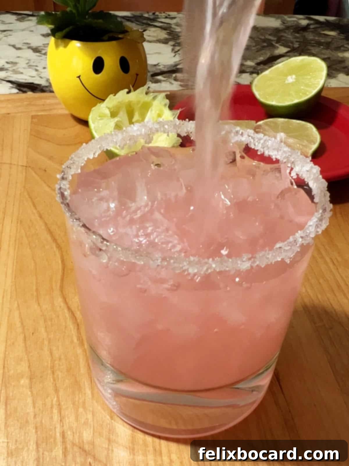 Blushing Grapefruit Margarita 7 Pouring the pink grapefruit margarita over ice in a prepared glass.