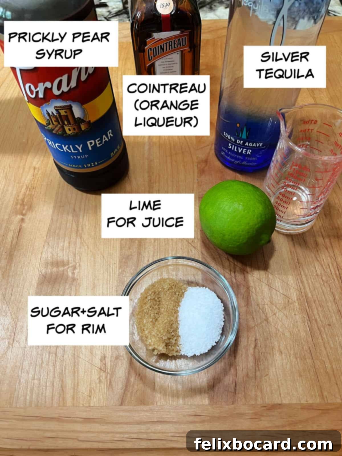 A selection of ingredients for the prickly pear margarita, including prickly pear syrup, Cointreau, tequila, fresh limes, sugar, and salt.
