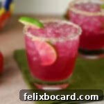 A vibrant prickly pear margarita, garnished with lime, ready to be enjoyed.