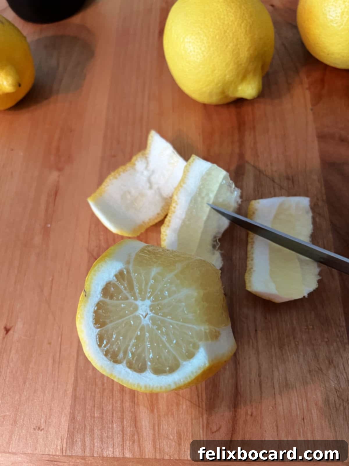 Desert Rose Lemonade 5 A hand cutting the peel from a whole lemon with a knife.