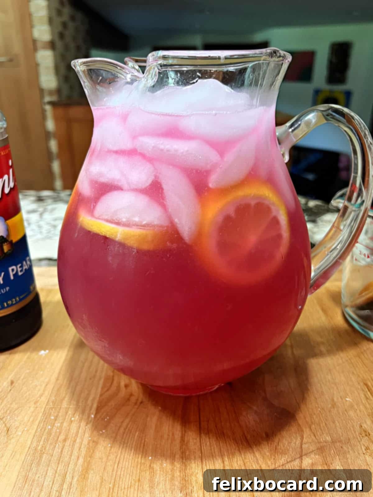 Desert Rose Lemonade 9 A pitcher of vibrant pink prickly pear lemonade, filled with ice and garnished with fresh lemon slices, ready to be served.