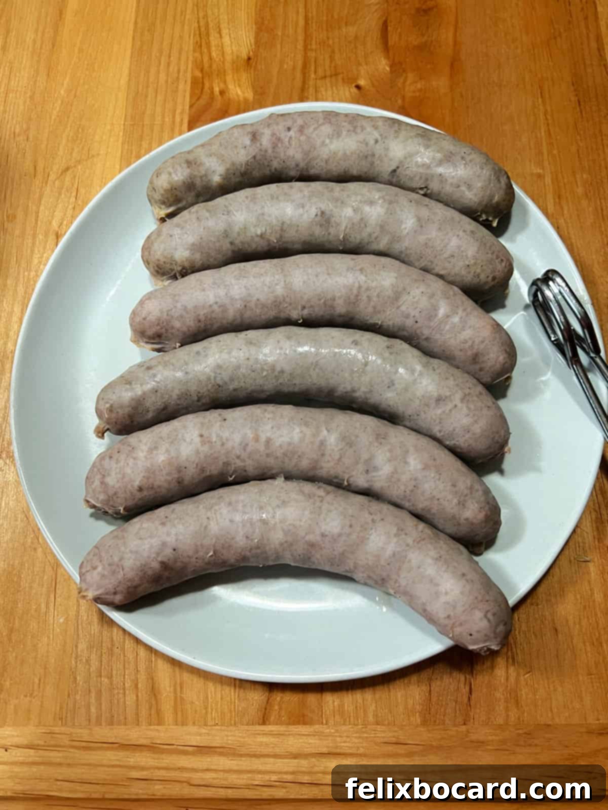 Classic Wisconsin Beer Brats 5 Parboiled bratwurst arranged on a plate, ready for grilling, showcasing their plump texture.