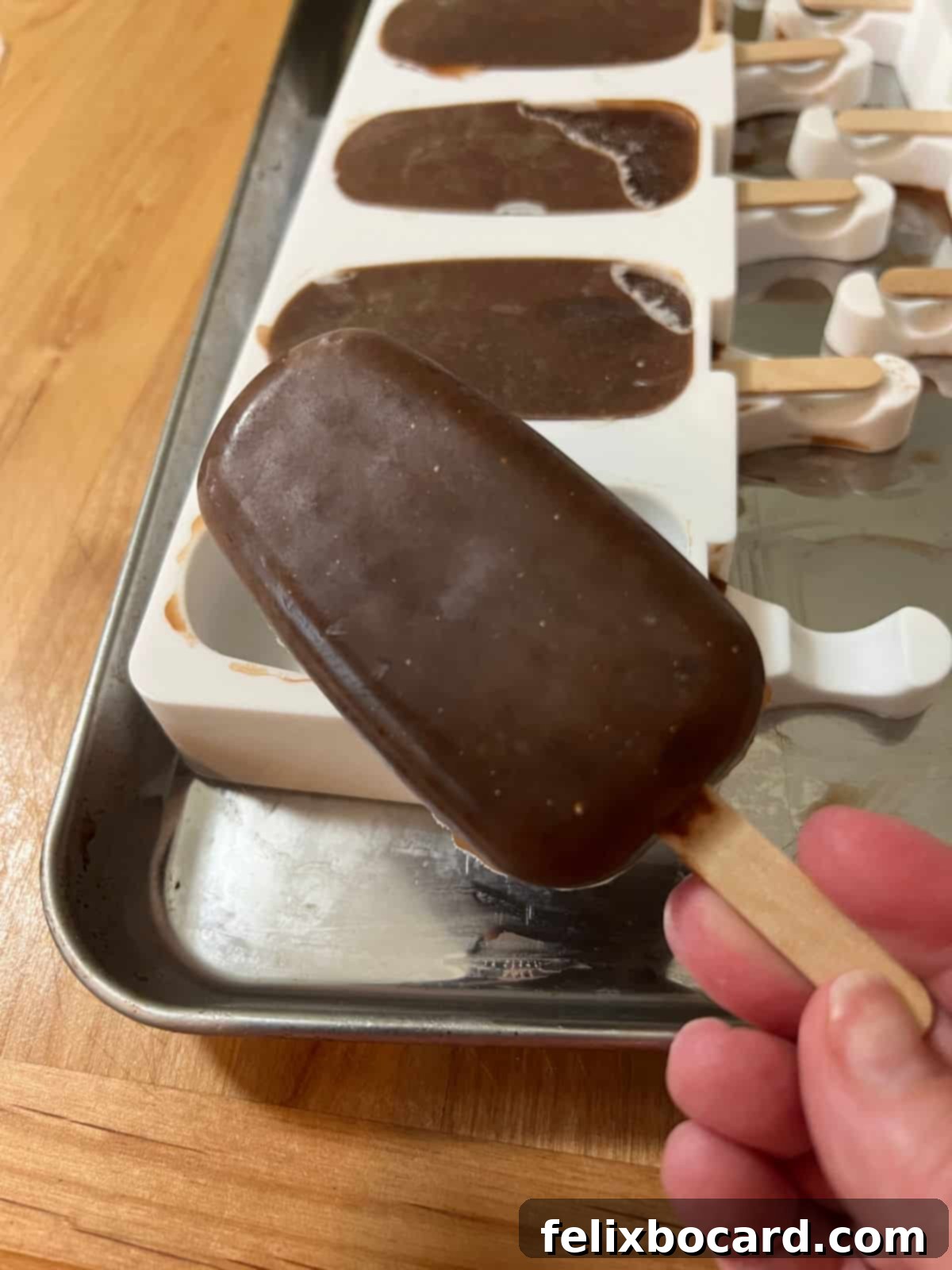 A single homemade fudgesicle, perfectly frozen and removed from its silicone mold, standing upright on a clean surface.