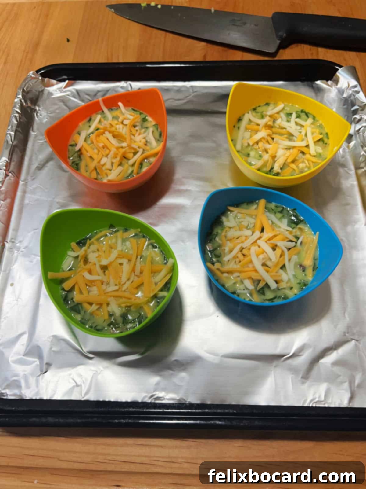 Uncooked egg bites in silicone cups, topped with a sprinkle of cheese.