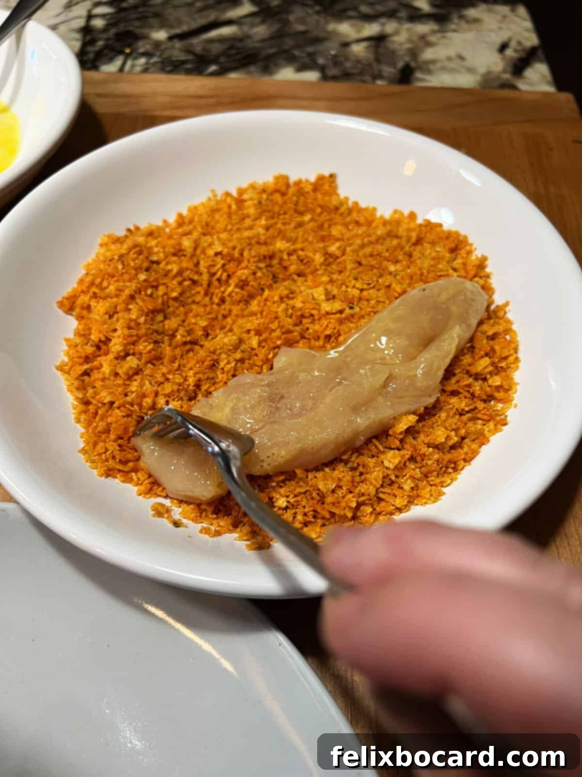 Crunchy Doritos Air Fryer Chicken Tenders 8 A chicken tender being coated thoroughly in crushed Doritos chips.