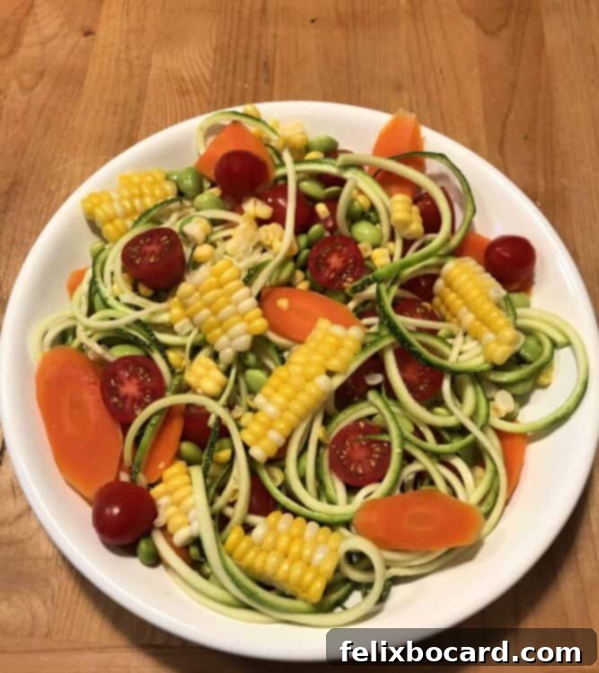 A beautifully arranged Confetti Corn Zoodle Bowl, showcasing fresh vegetables before dressing