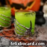 Monster Mash Punch 15 A skeleton hand decorated glass filled with yellow-green witches brew cocktail punch.