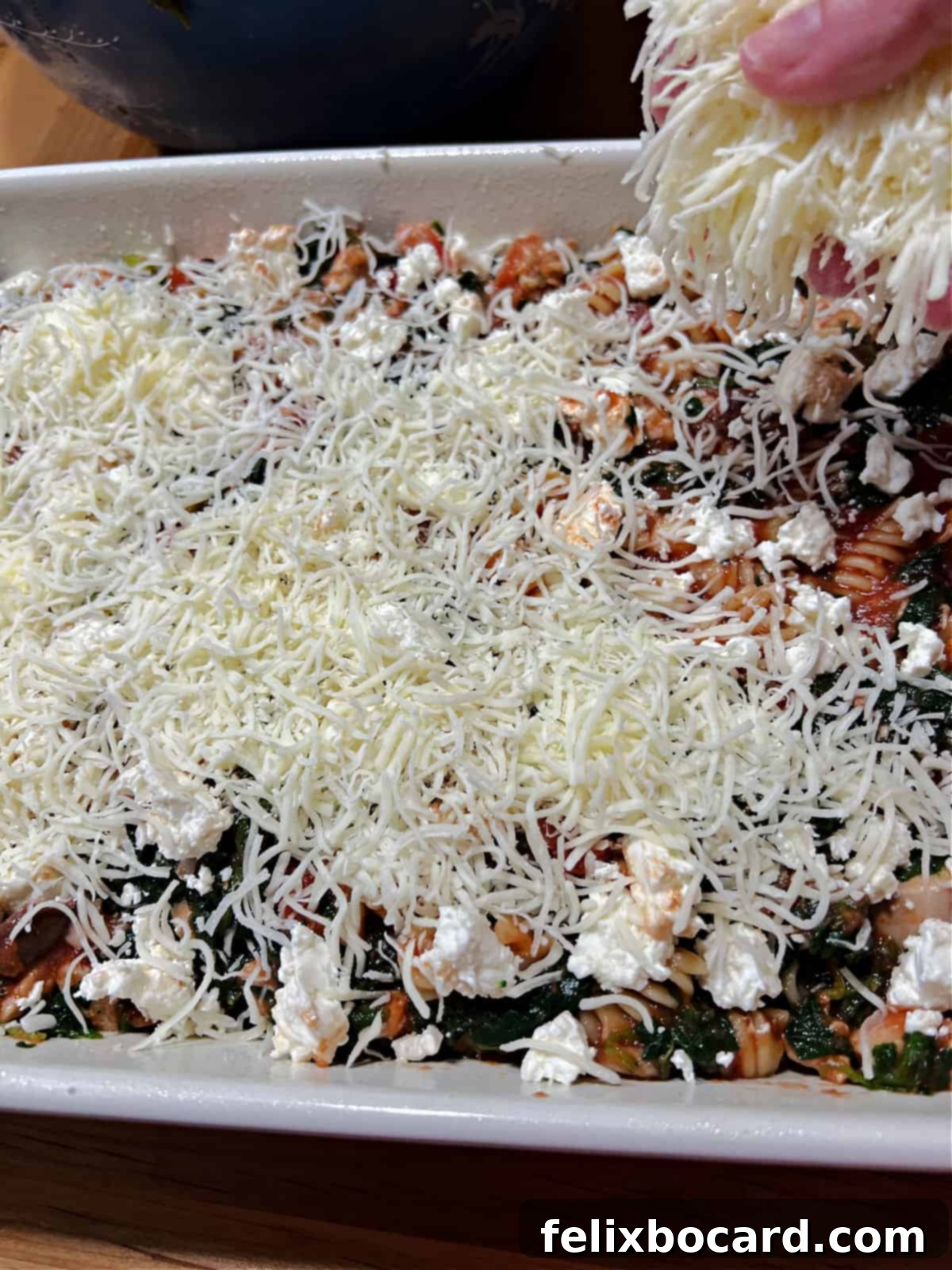 Adding cheese to the top of the casserole.