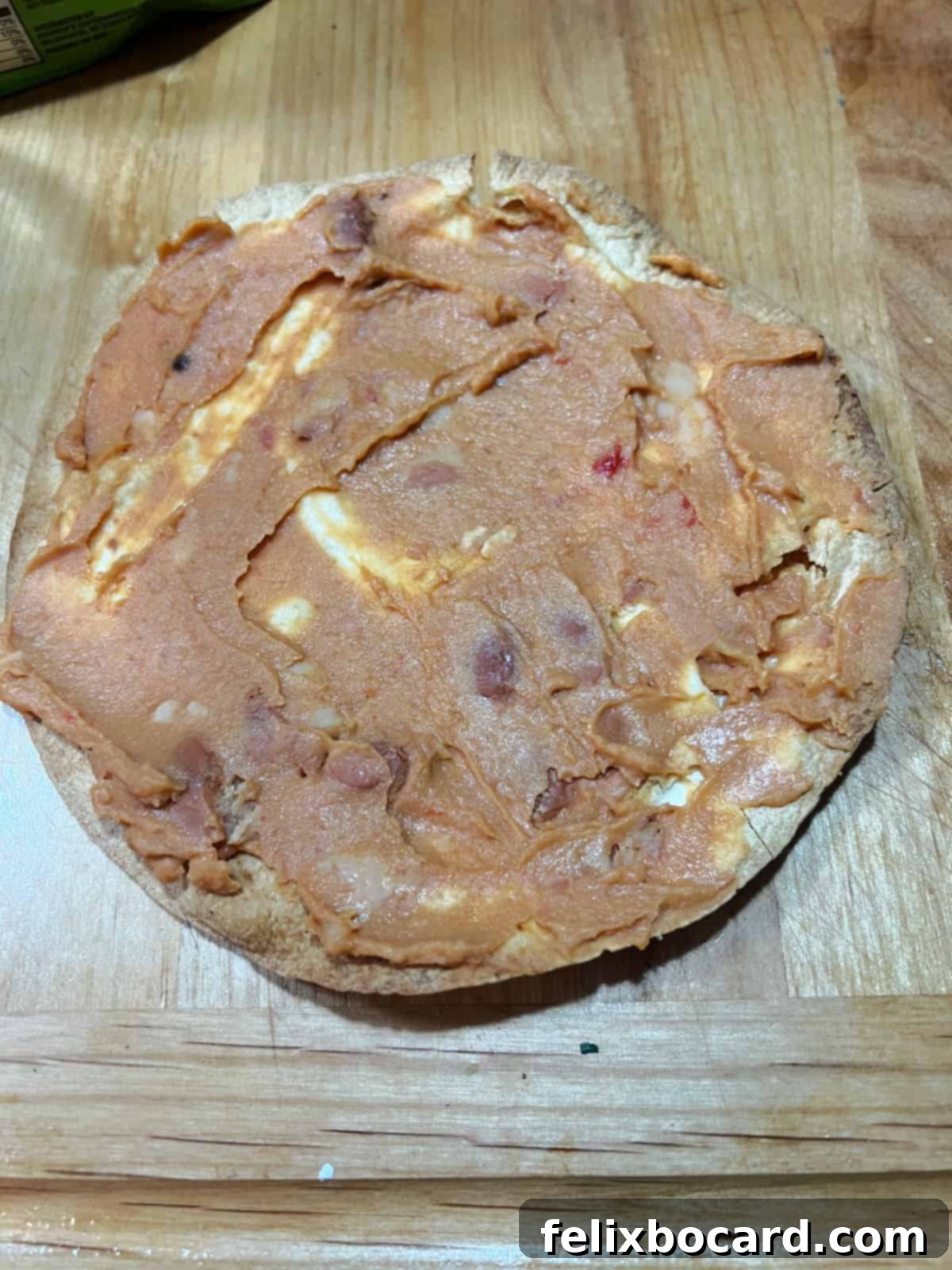 Cooked tortilla spread with a layer of refried beans.