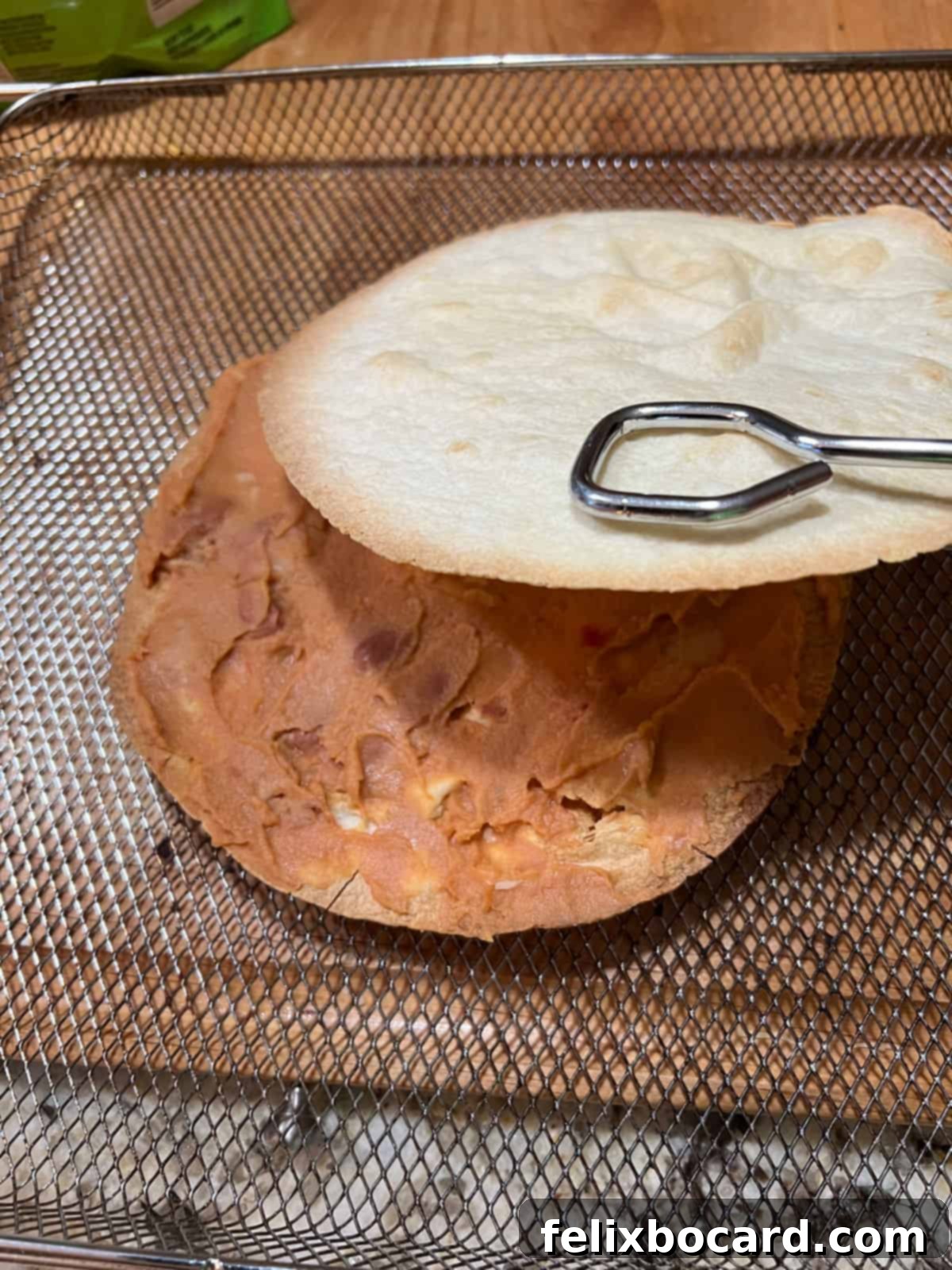 layering the second tortilla over the refried beans.