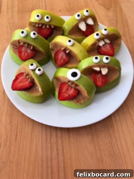 A group of silly apple bites on a white plate, showcasing various funny faces made with fruit, nut butter, and edible eyes.