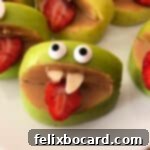 Close up of one silly apple bite with googly eyes and strawberry tongue.