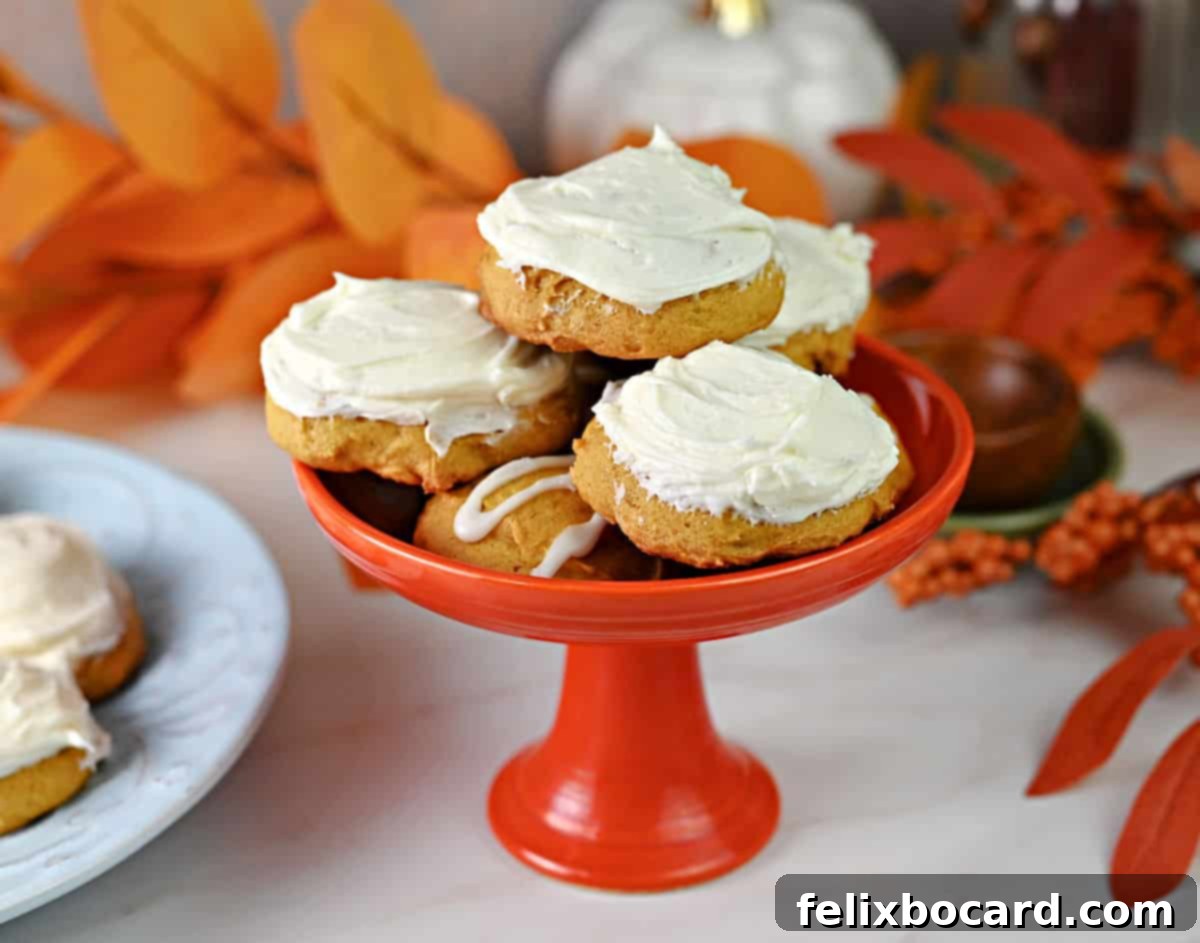 Old fashioned pumpkin cookies stacked in a small stemmed serving dish, generously frosted with creamy cream cheese frosting.