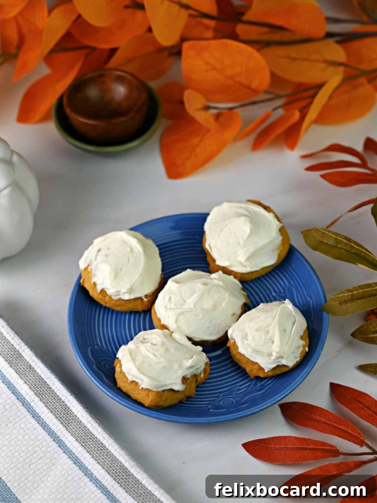 Small blue plate containing 5 old fashioned pumpkin cookies with cream cheese frosting, ready to eat.
