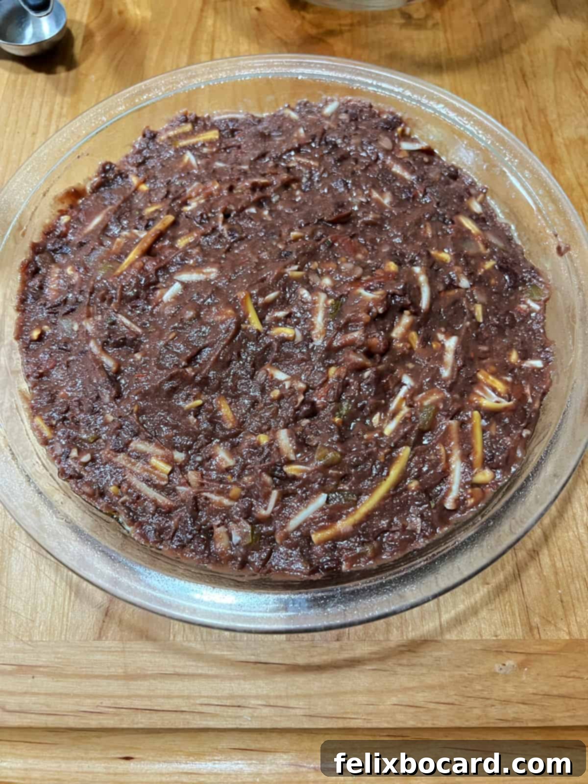 The savory black bean dip mixture smoothly spread into a 9-inch pie plate, ready for baking and subsequent spider web decoration.