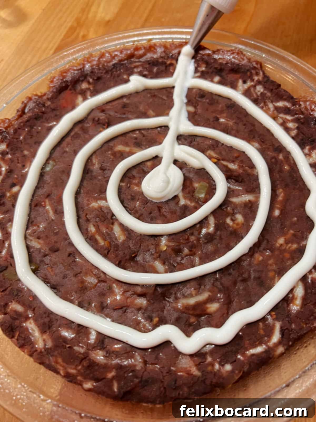 Radial lines are drawn from the center through the concentric sour cream circles on the dip, completing the intricate spider web pattern for a spooky Halloween effect.