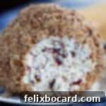 More Than Twenty Dried Cranberry Creations 6 A festive cranberry cheese ball adorned with nuts and herbs, ready for serving.