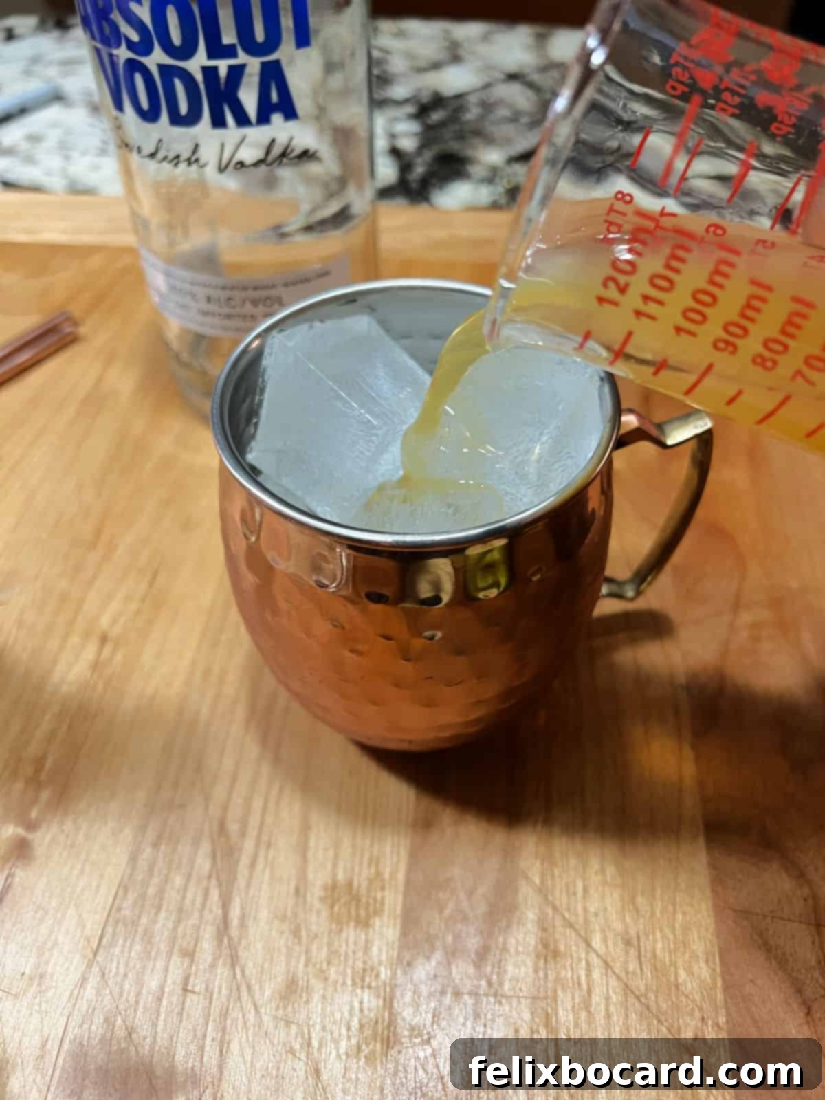 Spiced Apple Moscow Mule 4 Pouring ingredients into an ice-filled copper mug for an Apple Cider Moscow Mule.