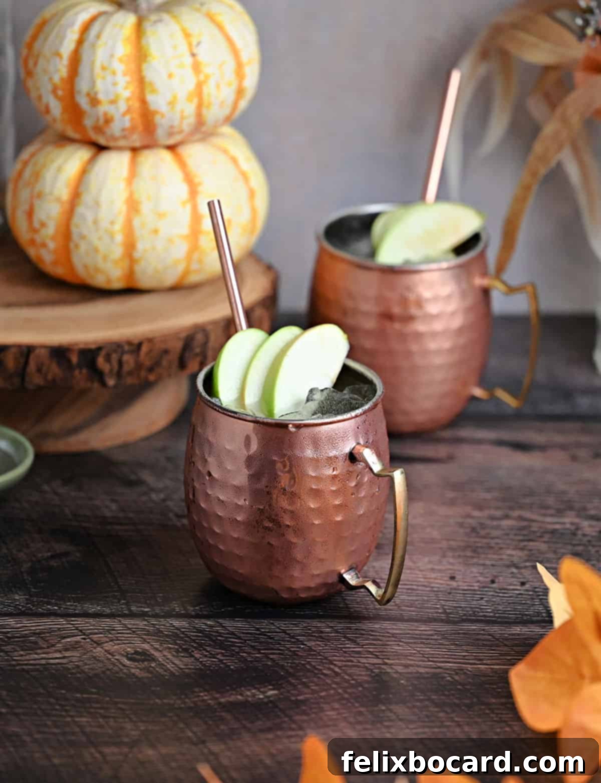 Spiced Apple Moscow Mule 6 Two apple-garnished copper mugs filled with delicious Apple Cider Moscow Mules, ready to be enjoyed.