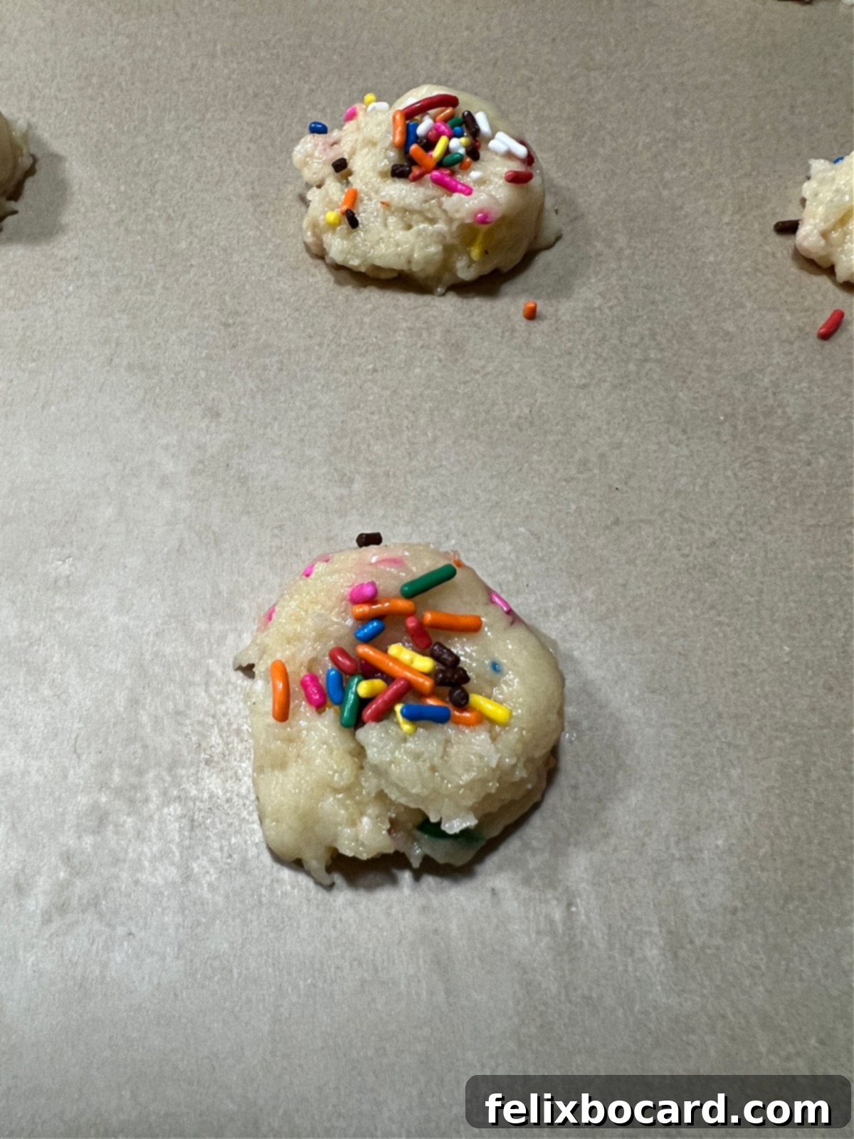 Funfetti cookie dough balls with additional sprinkles placed on top before baking.