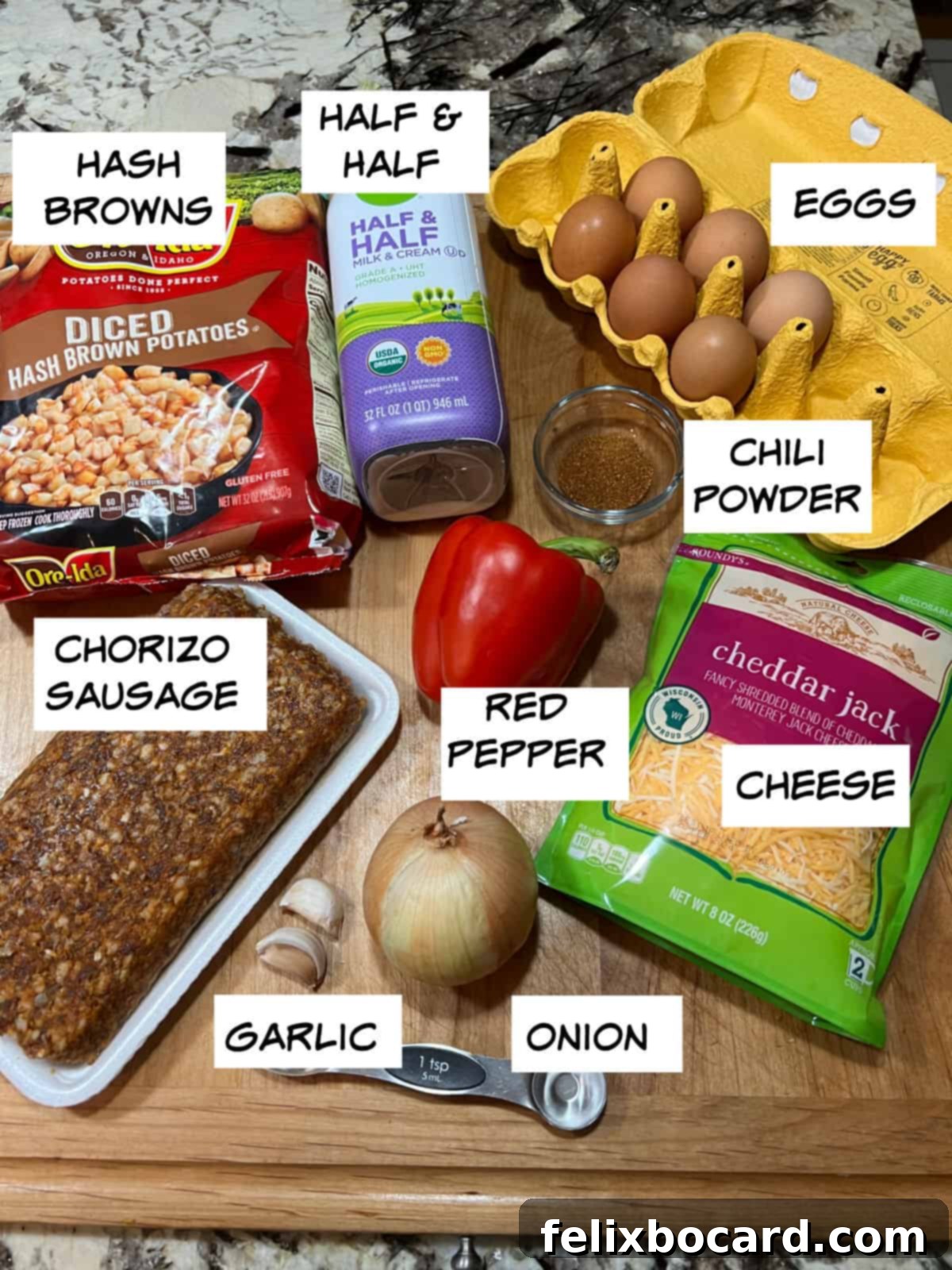 A flat lay photograph showcasing the key ingredients: raw chorizo sausage, eggs, half-and-half, shredded cheese, diced red bell pepper, diced onion, minced garlic, and cubed hash browns.