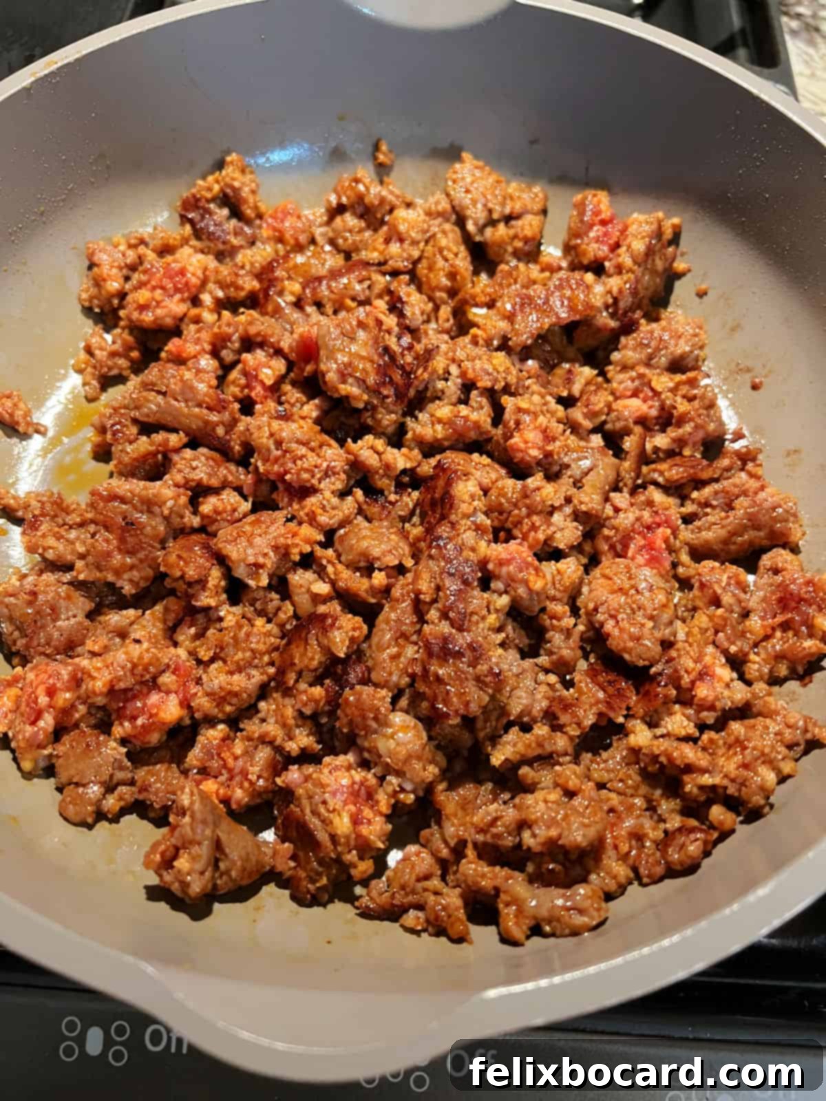 Crumbled chorizo sausage cooking in a nonstick skillet, turning golden brown and fragrant.