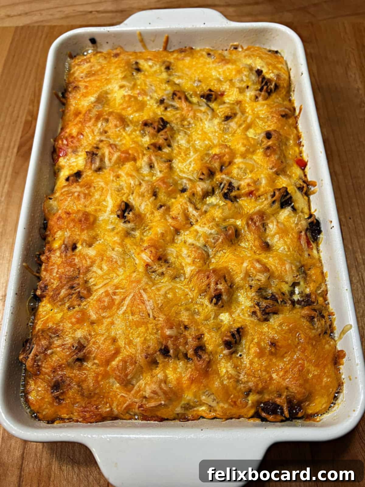 A freshly baked Chorizo Egg Bake casserole in a baking dish, showing a golden, melted cheese top and bubbly edges.