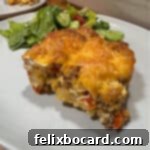 Serving of chorizo egg bake on a plate with a green salad.