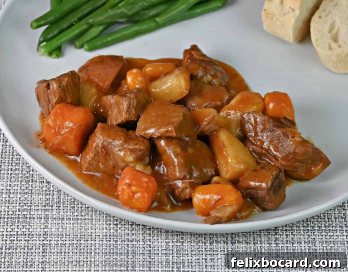 Instant Pot beef stew generously served on a white plate, accompanied by vibrant green beans and a slice of crusty bread, illustrating a complete and inviting meal.