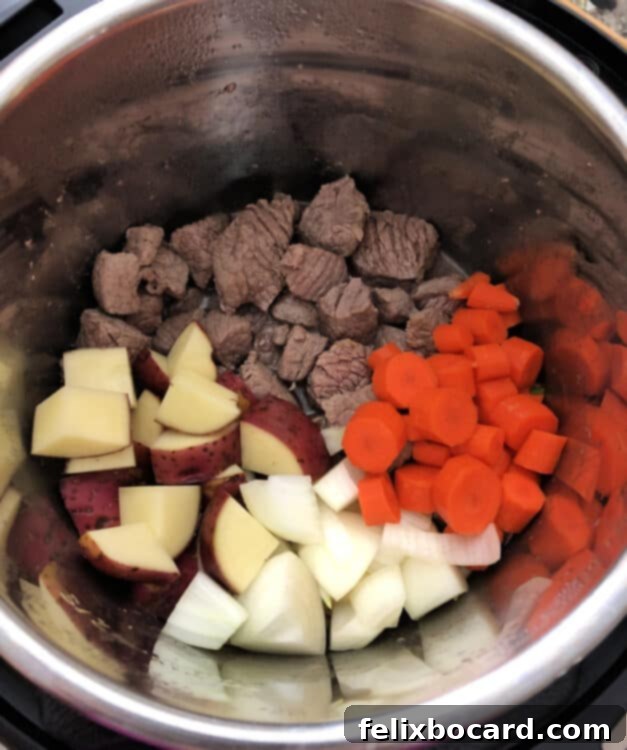 Preparing ingredients for beef stew: a cutting board with cubed beef, chopped carrots, and potatoes.